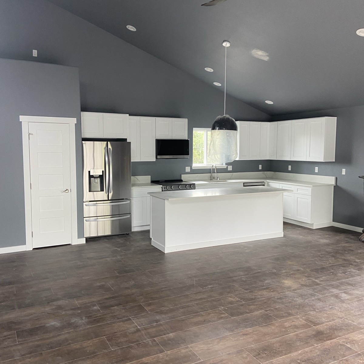 Finished kitchen remodel with island, white cabinets, and stainless appliances