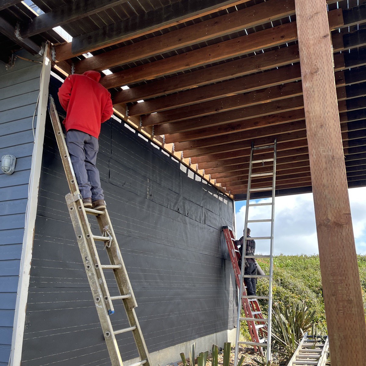 Crew installing roof underlayment membrane